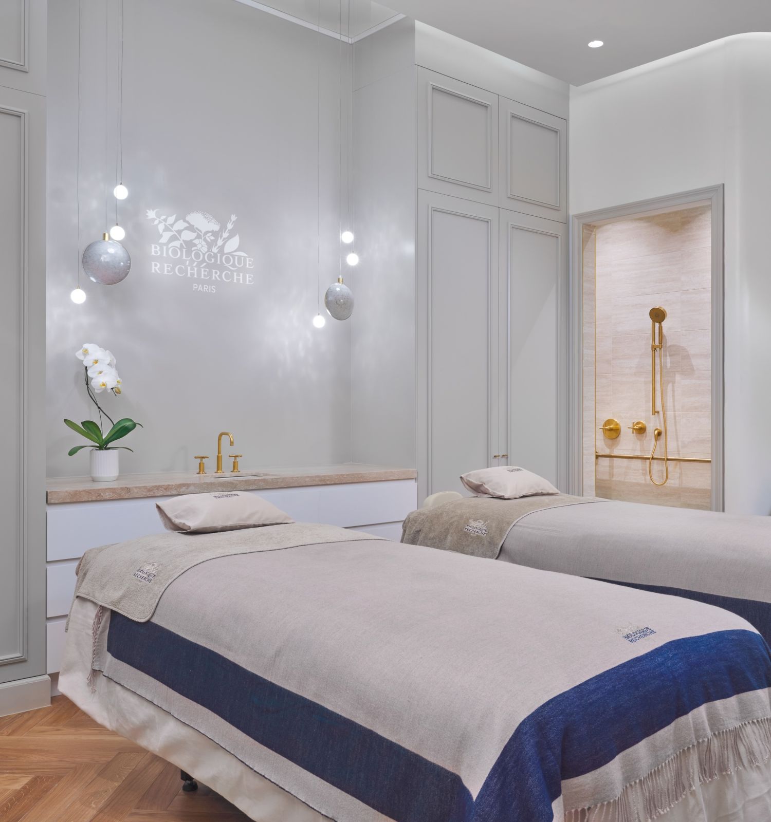 A spa room with two massage tables and a shower.