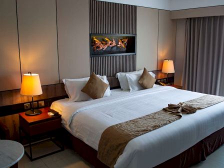 A hotel room with a large bed and warm lamps.